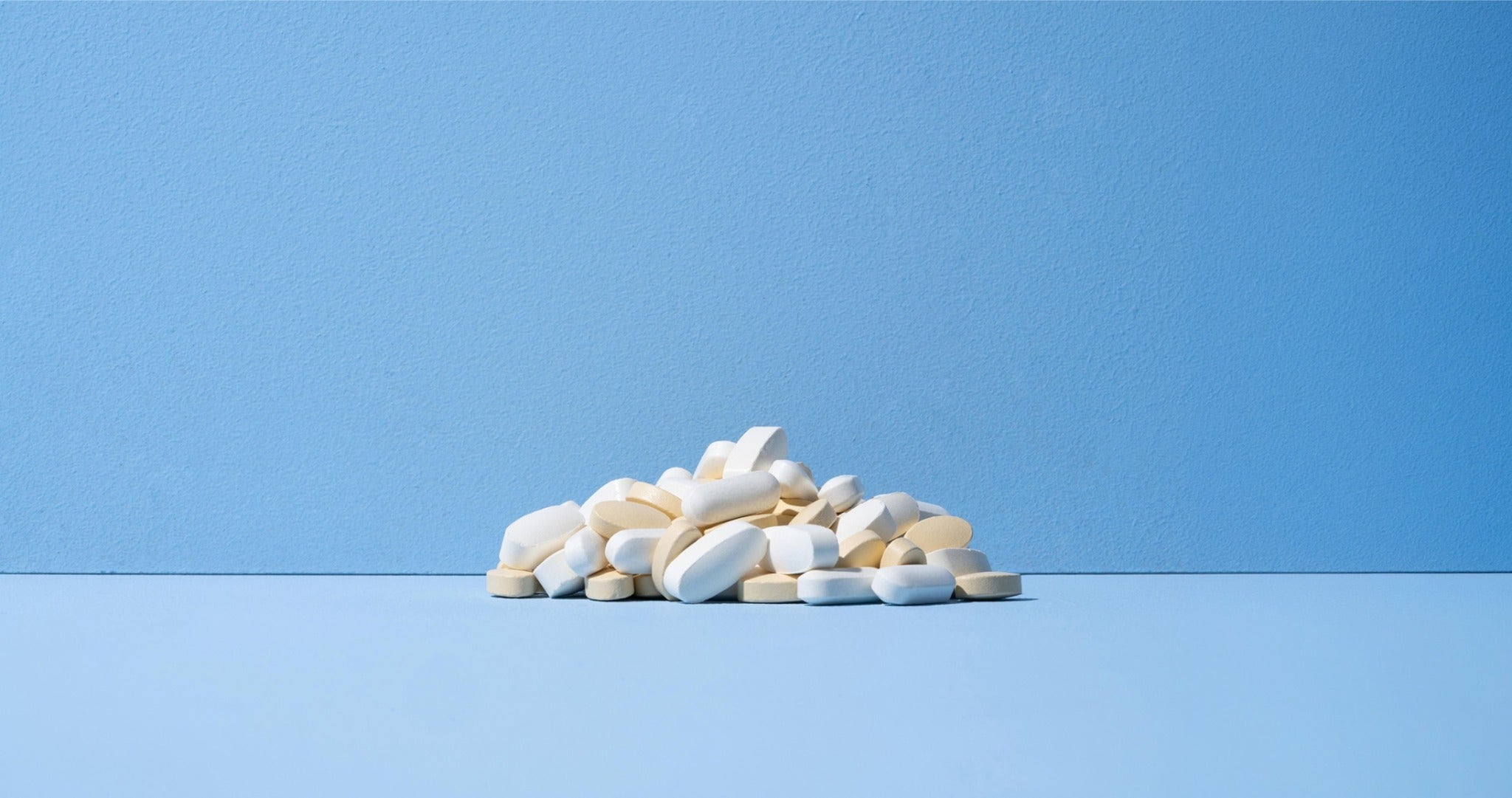 A centred pile of separate supplement tablets on a blue background